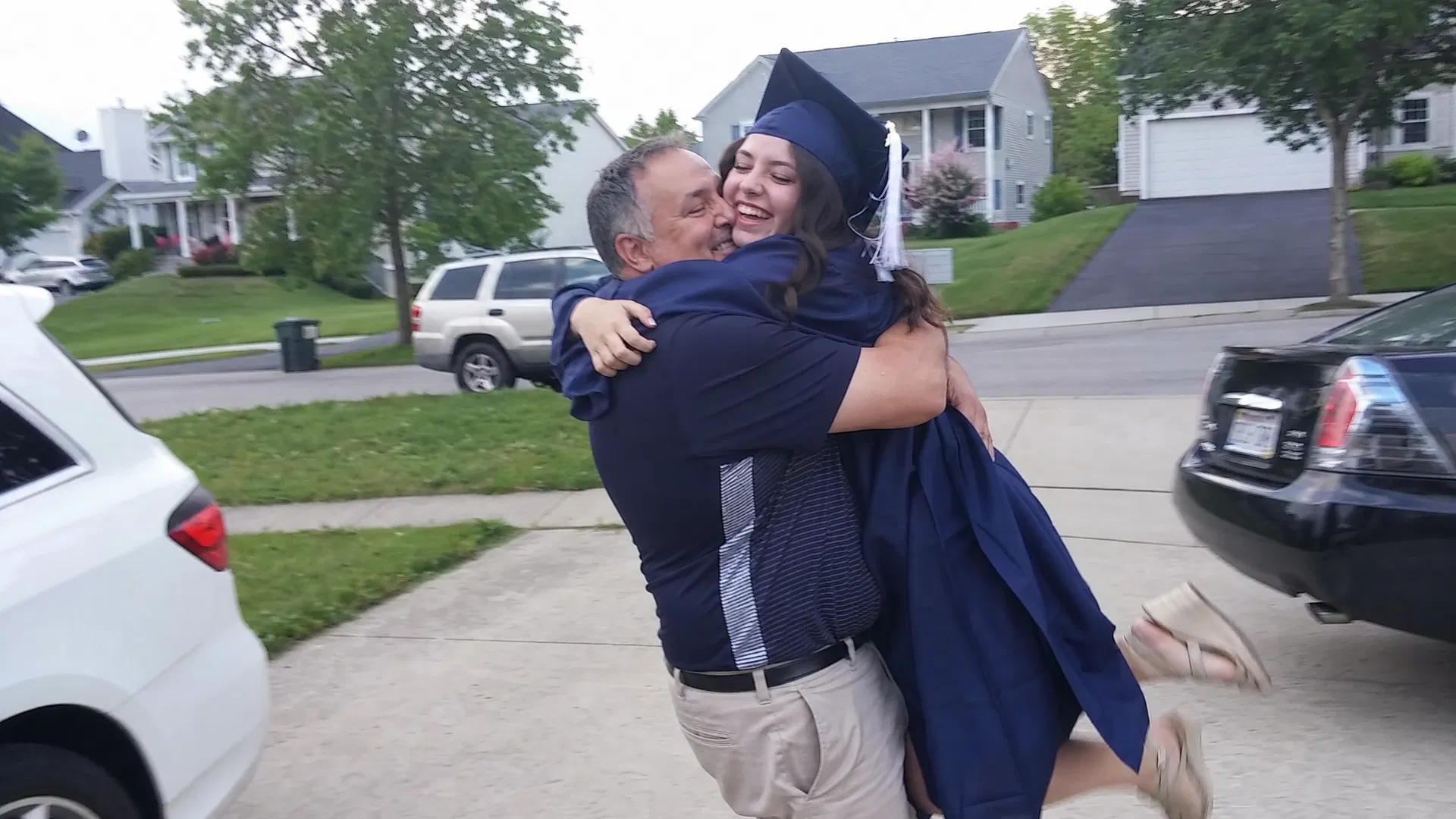 Dad lifting his daughter in a big hug after her graduation ceremony, both laughing