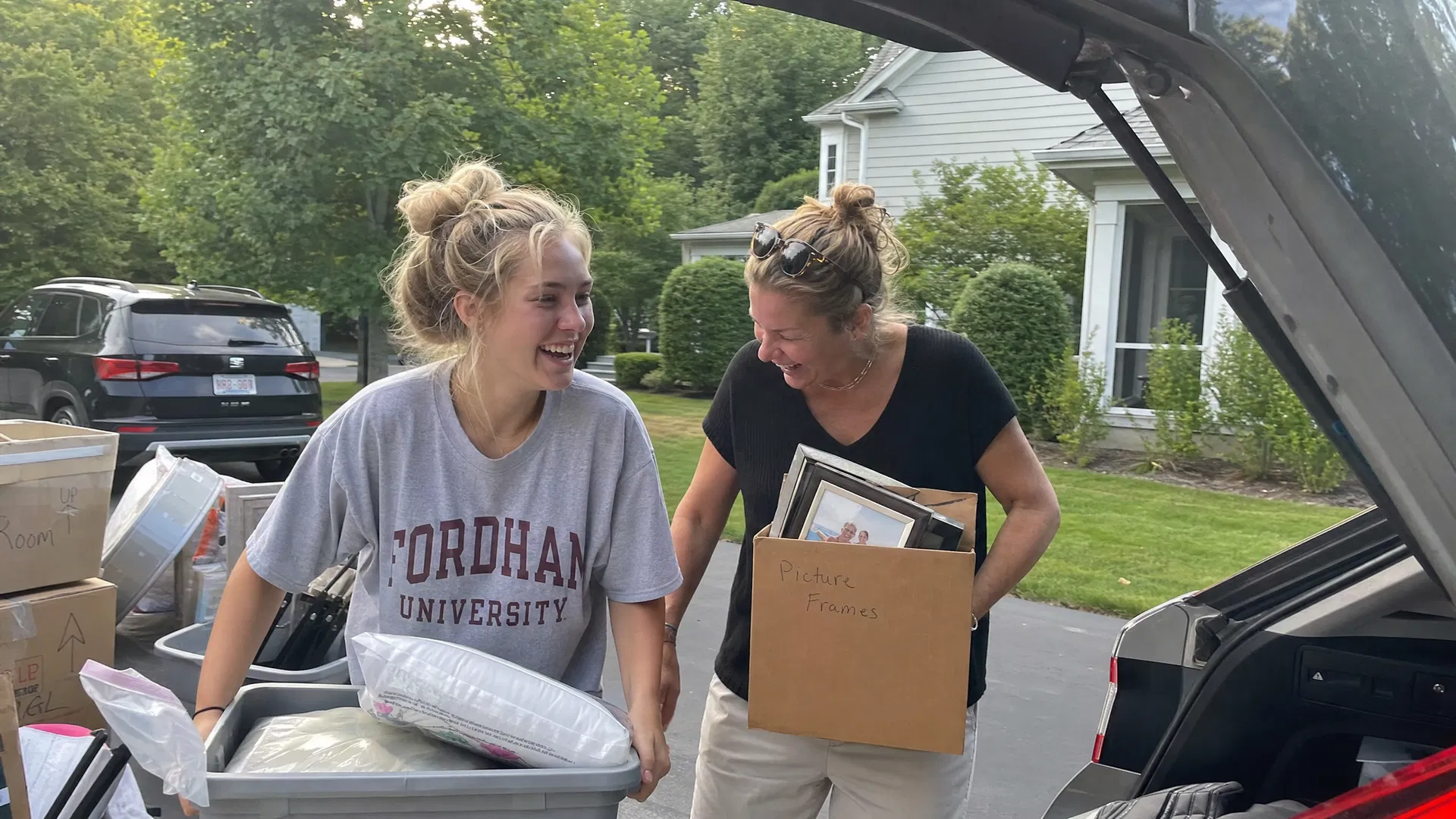 Mom and daughter laughing while loading boxes into the car for college move-in day
