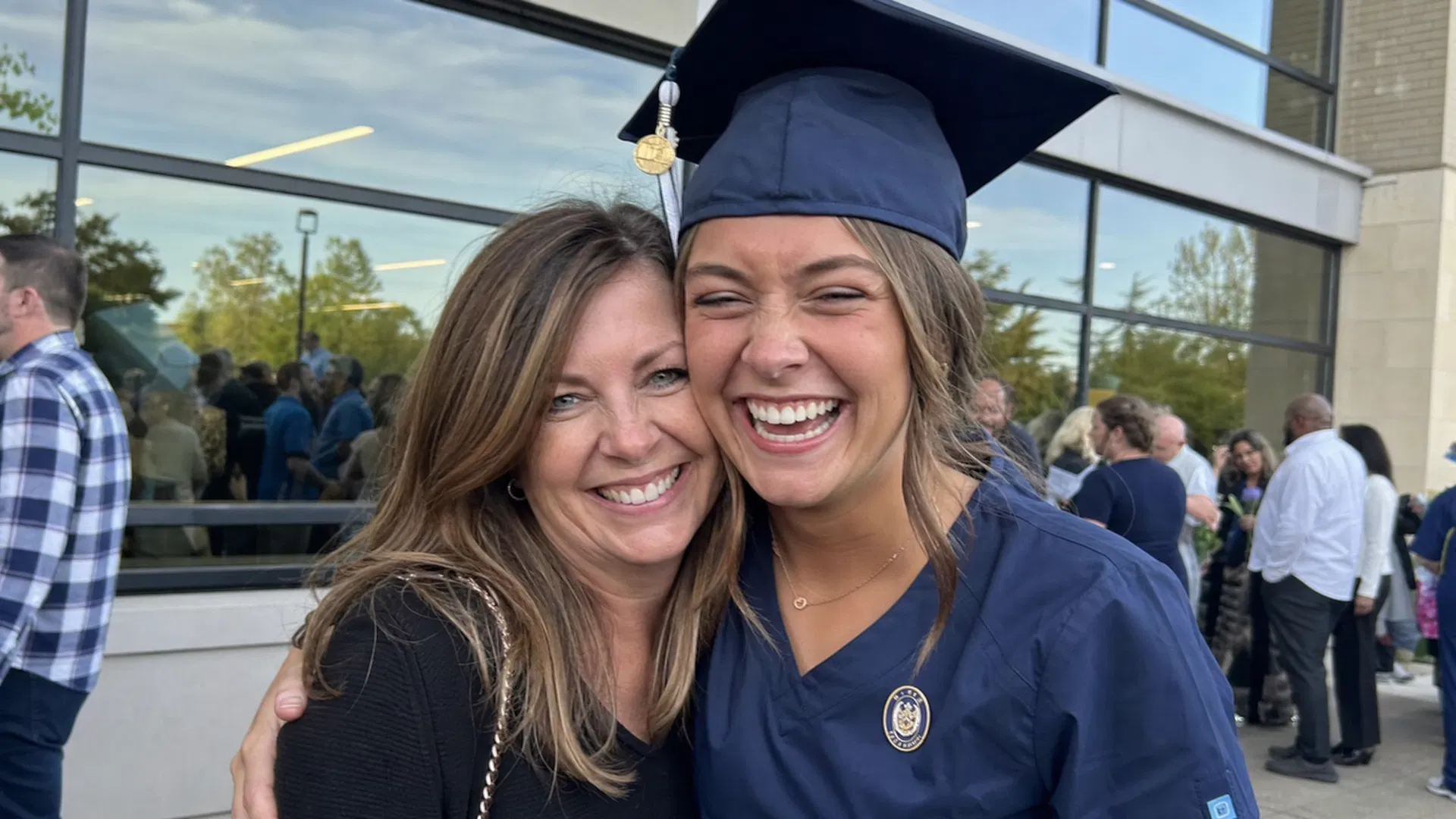 Nursing school graduate in scrubs holding diploma, smiling