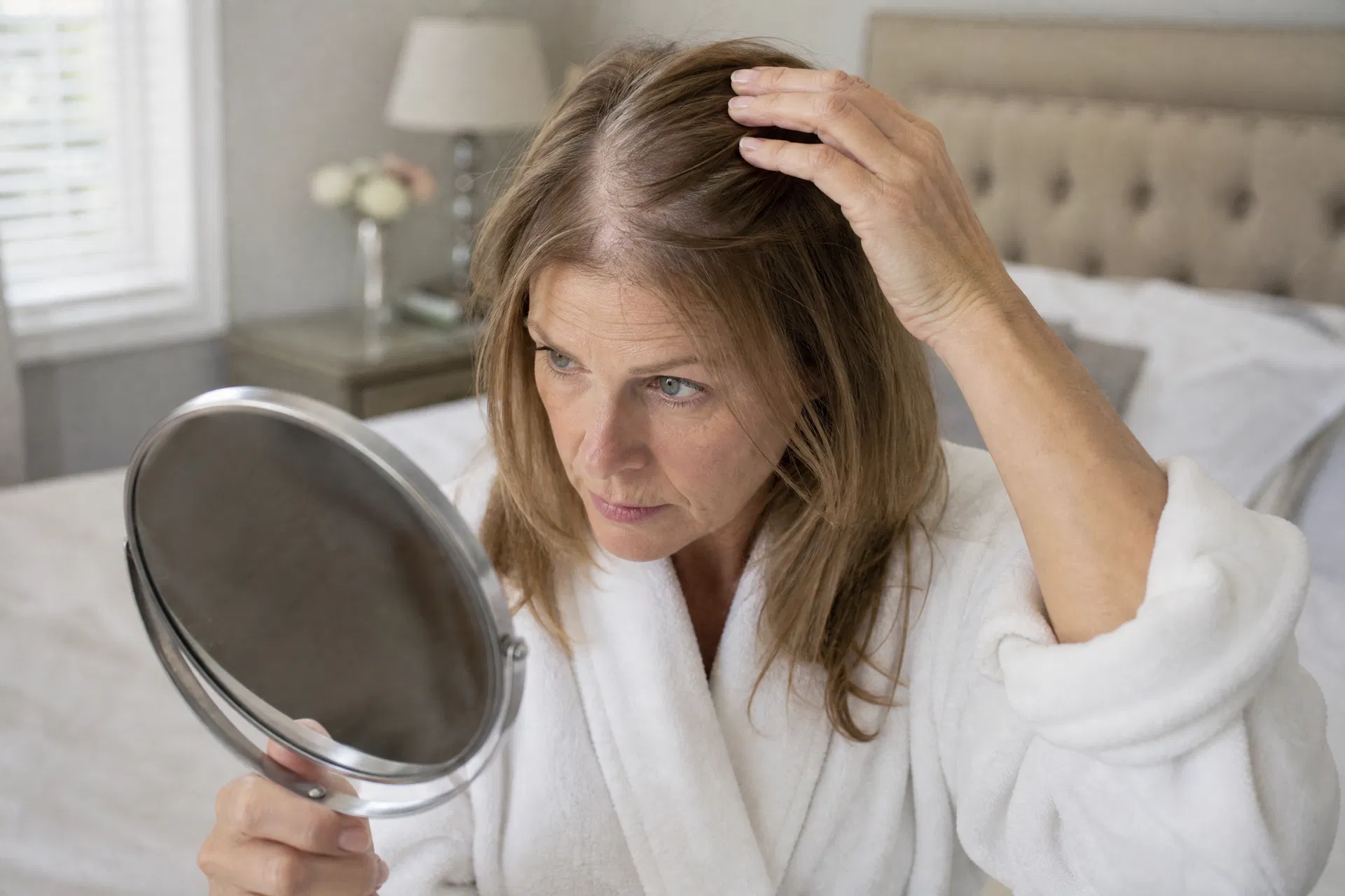 Woman checking thinning hair in mirror