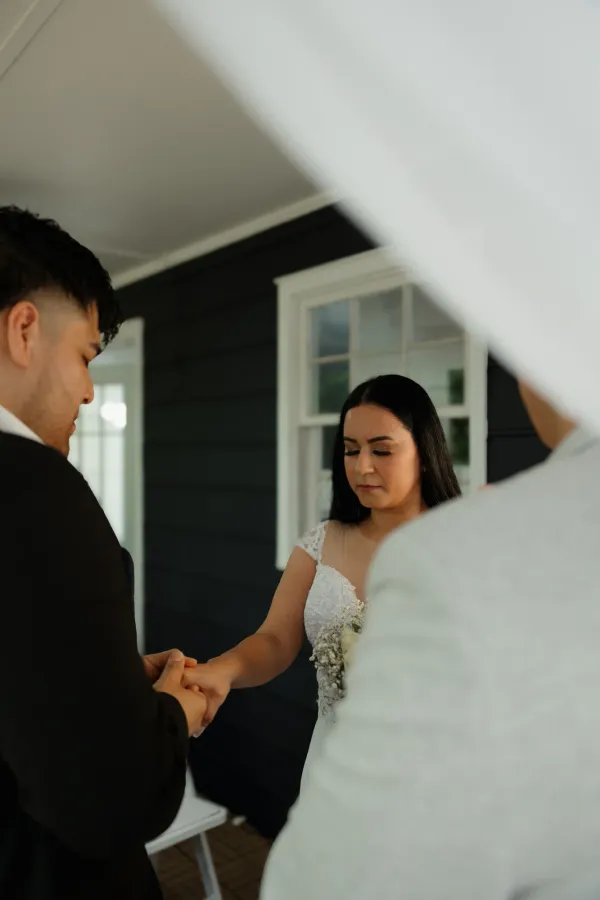 Close-up of bride and groom holding hands during a wedding ceremony, with the bride looking down thoughtfully.