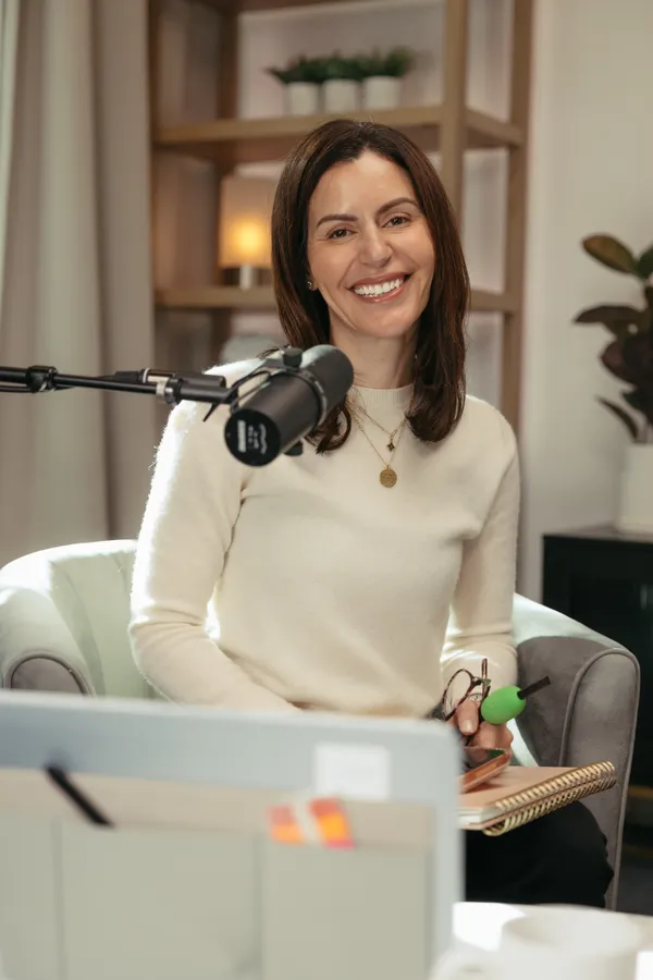 Smiling woman recording a podcast in a professional studio with a microphone, ideal for branding photography in Charlotte, NC.