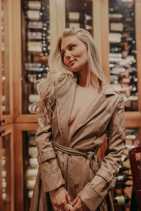 Elegant blonde woman in a stylish tan trench coat, looking chic in a sophisticated setting, captured by Gina Alex Creative in Charlotte NC.
