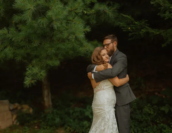 Groom kissing bride’s forehead as they look into the distance