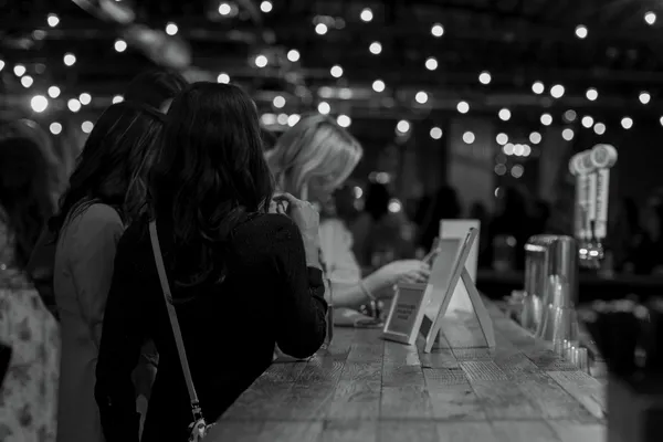 Black and white photo of women at a bar during a Galentine's Day event, with bokeh lights in the background, Charlotte NC