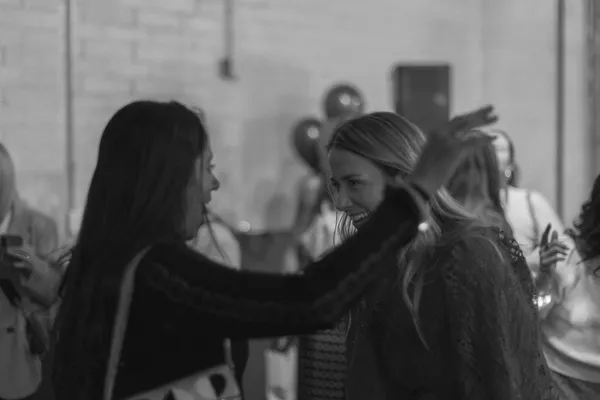 Two women laughing and interacting joyfully at a Galentine's Day party, black and white photograph.