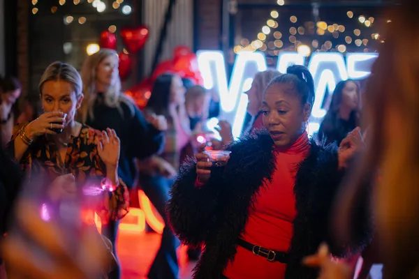 Women celebrating Galentine's Day with drinks and festive neon lights in Charlotte, NC, captured by Gina Alex Creative.