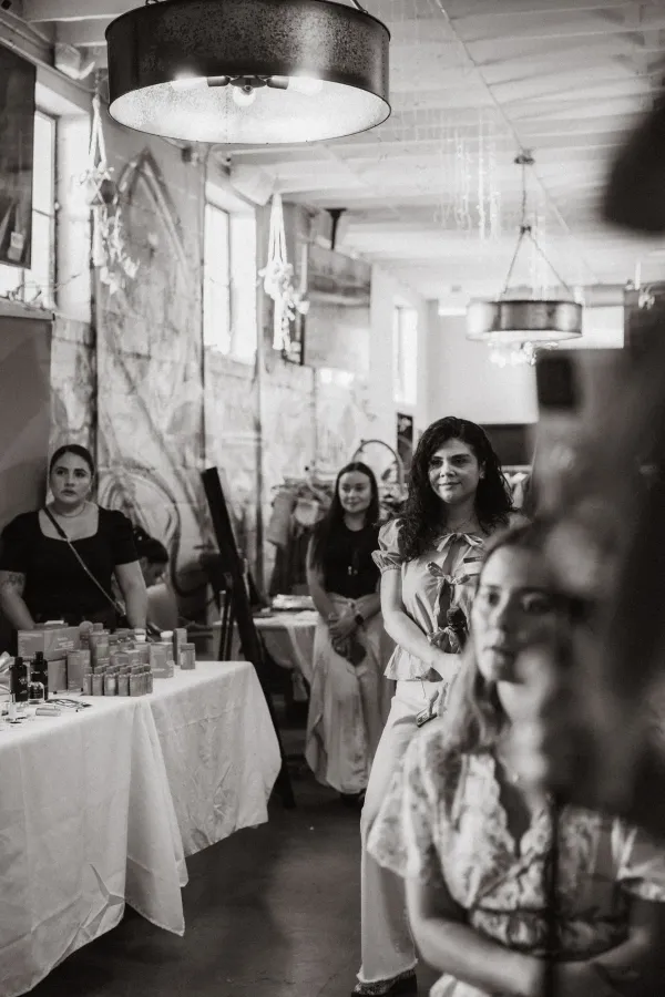 Black and white photo of a speaker with a microphone at an indoor event, with attendees in the background.
