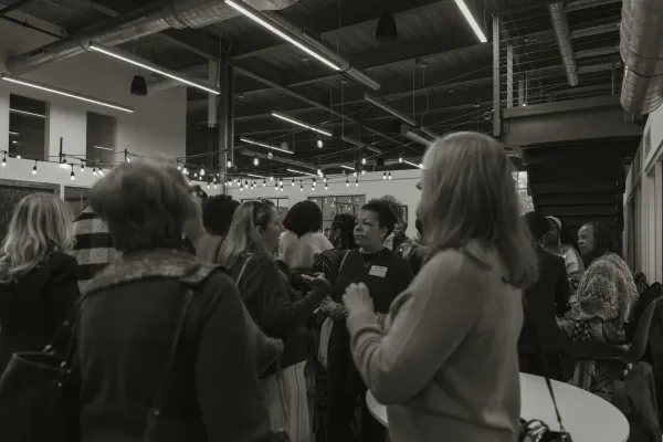 Black and white photo of diverse group of women networking and conversing at an indoor event in Charlotte.