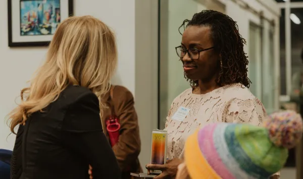 Woman with dreadlocks and glasses networking at an event, holding a drink, in Charlotte NC.