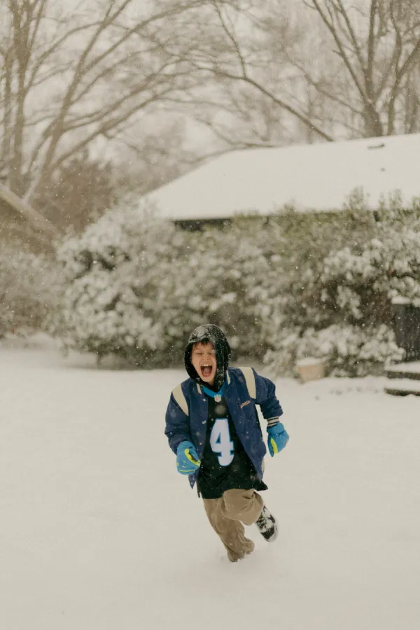 Excited boy in Carolina Panthers jacket running and shouting in the snow, Charlotte NC