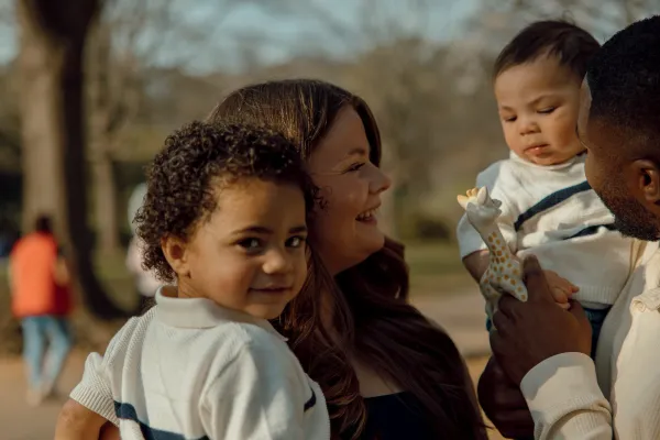 Diverse family of four, two parents and two young children, smiling outdoors in Charlotte, NC.