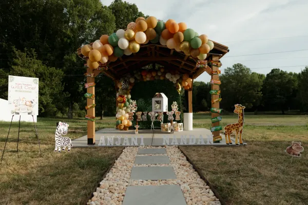 Outdoor jungle-themed 'Wild One' birthday party setup with balloons, animal cutouts, and a gazebo.