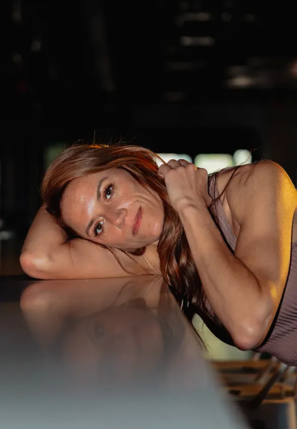 Woman with long hair resting head on reflective surface, warm lighting, Charlotte lifestyle portrait.