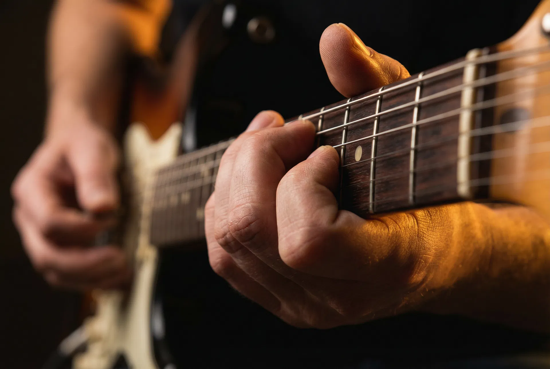 Close-up of guitarist hands pressing strings on a fretboard