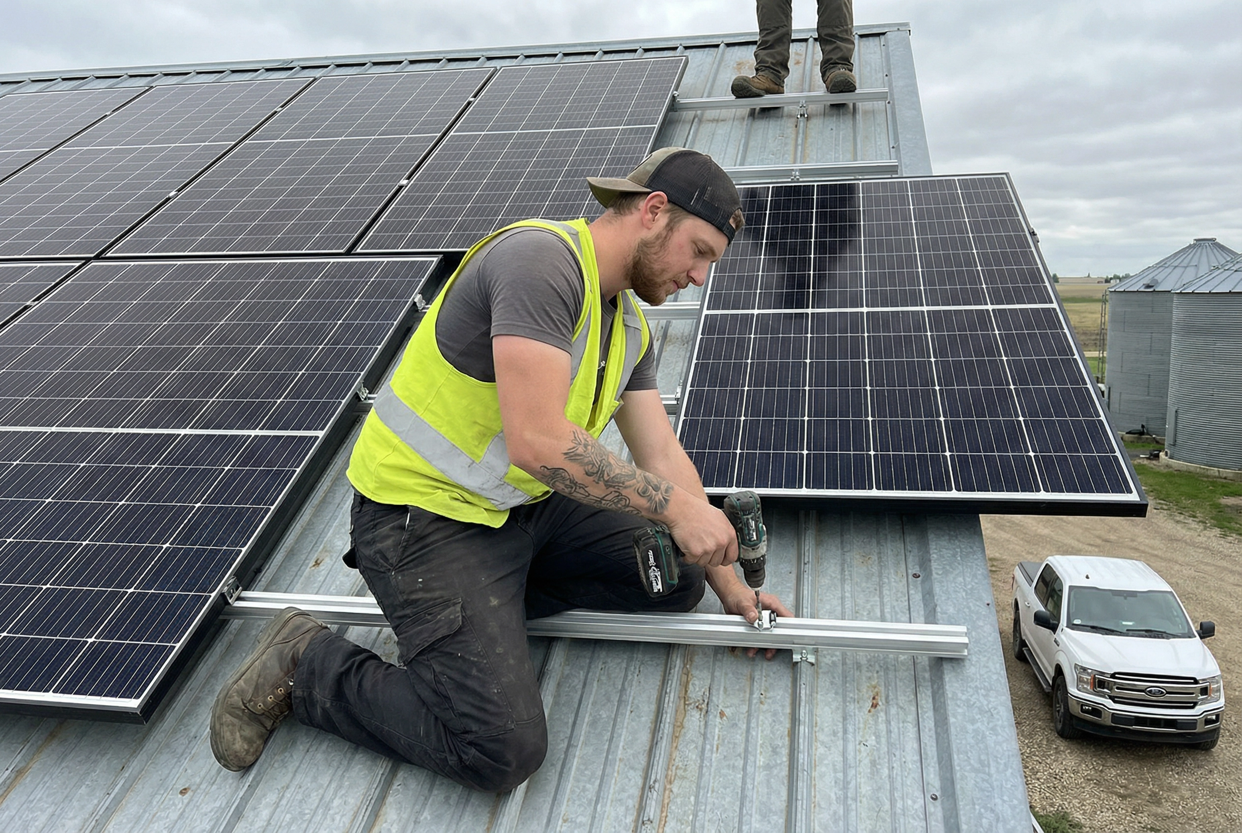Range Road Solar installer securing black solar panels to horizontal racking on a metal shop roof in Alberta