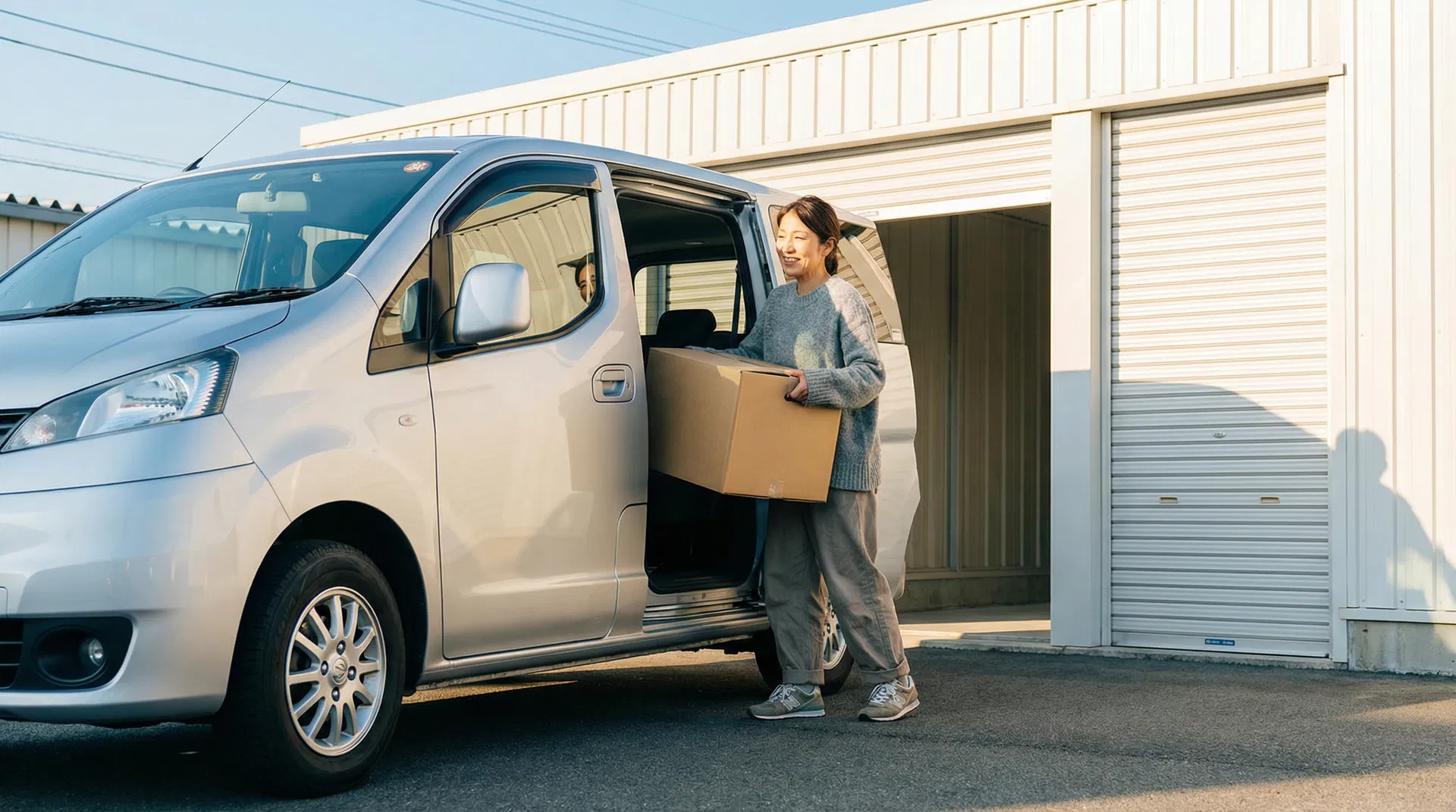 車を横づけして荷物を運ぶ女性