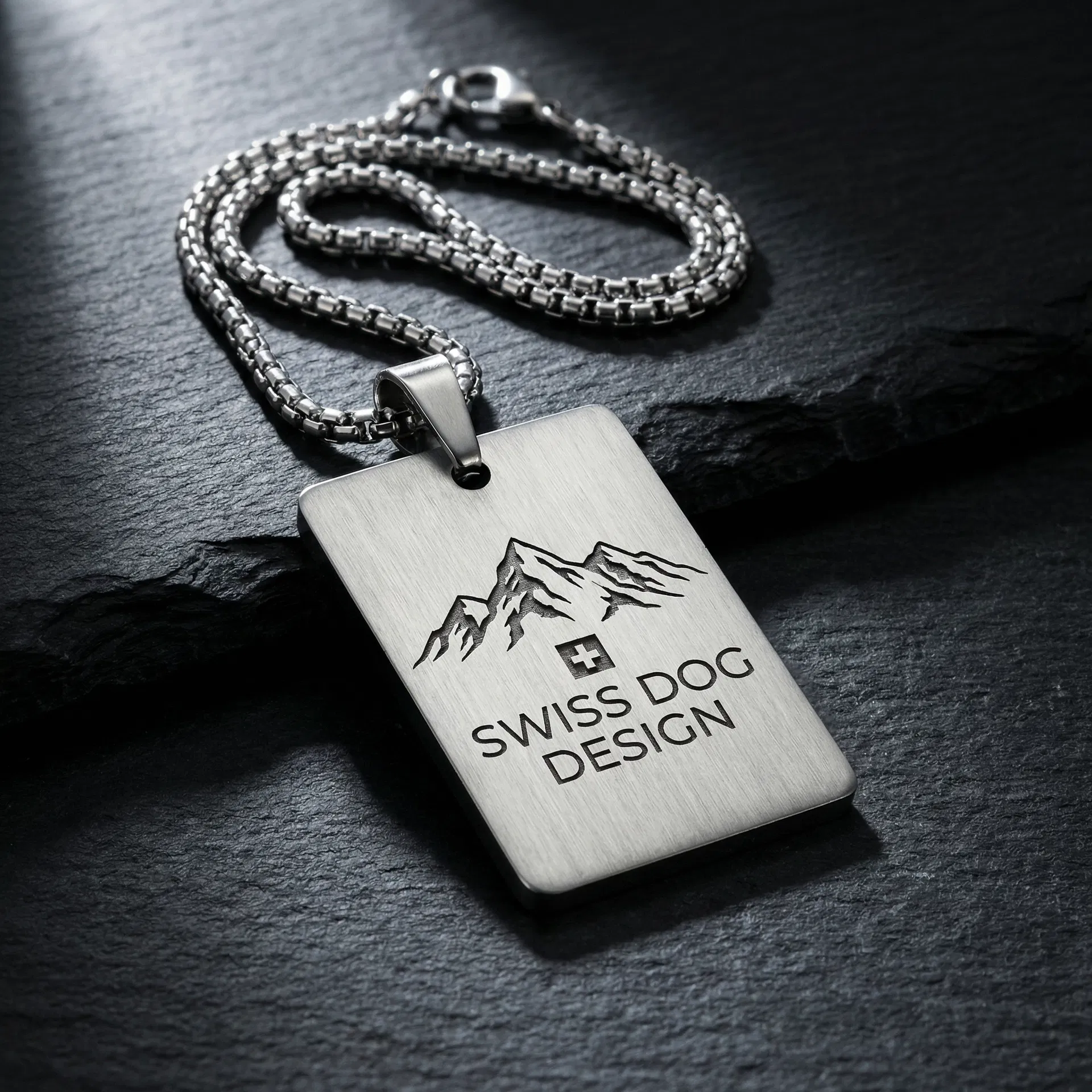 Colgante en acero inoxidable con motivo de montañas y cruz suiza grabados