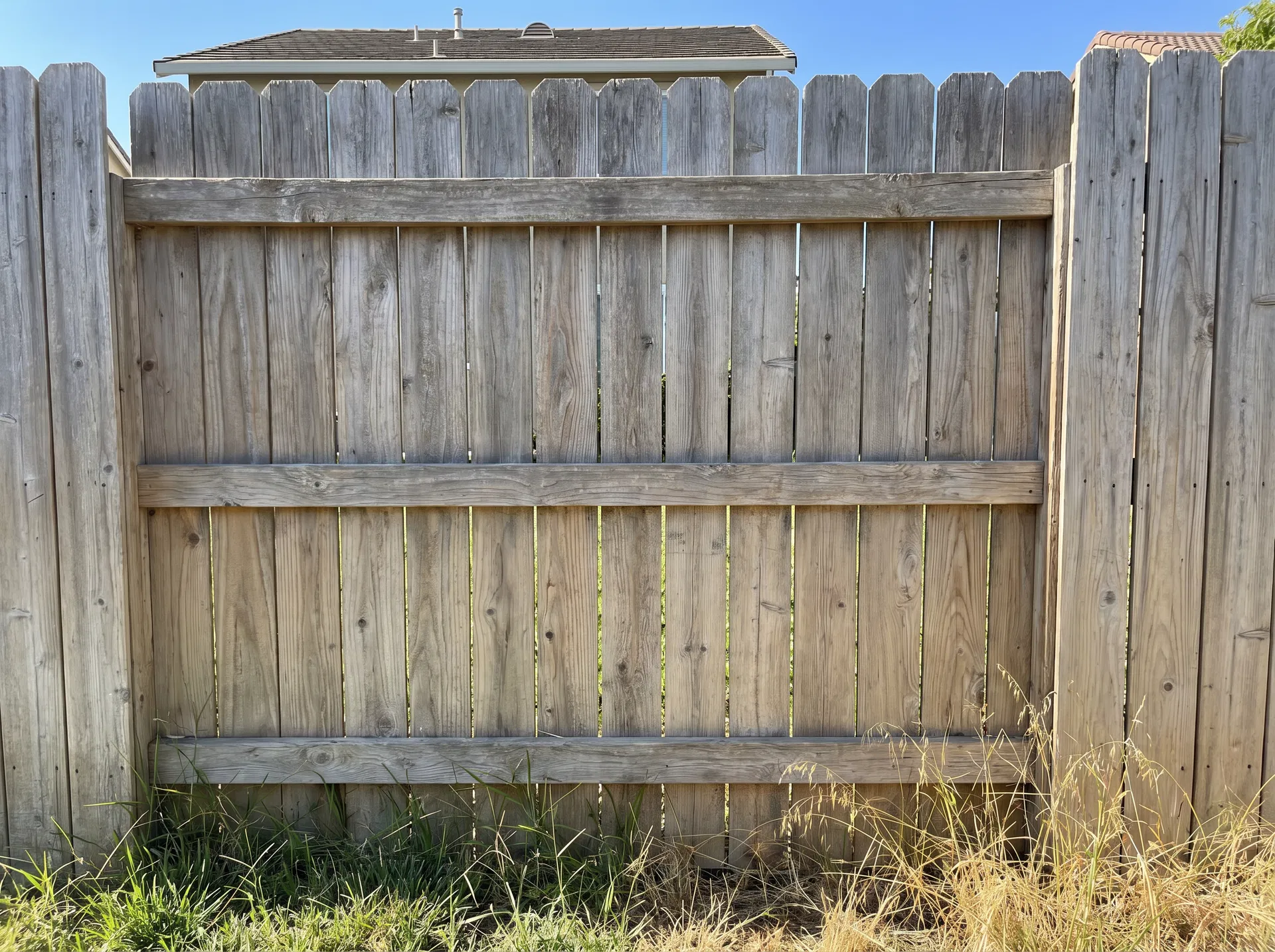 A slightly faded cedar fence — grey, a little tired, but structurally sound