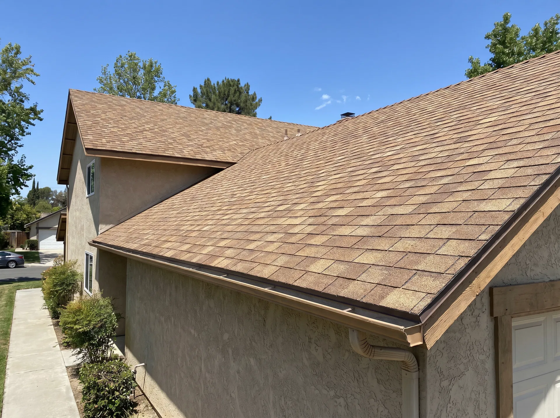 A residential shingle roof seen from the ground — looks fine, maybe slightly faded