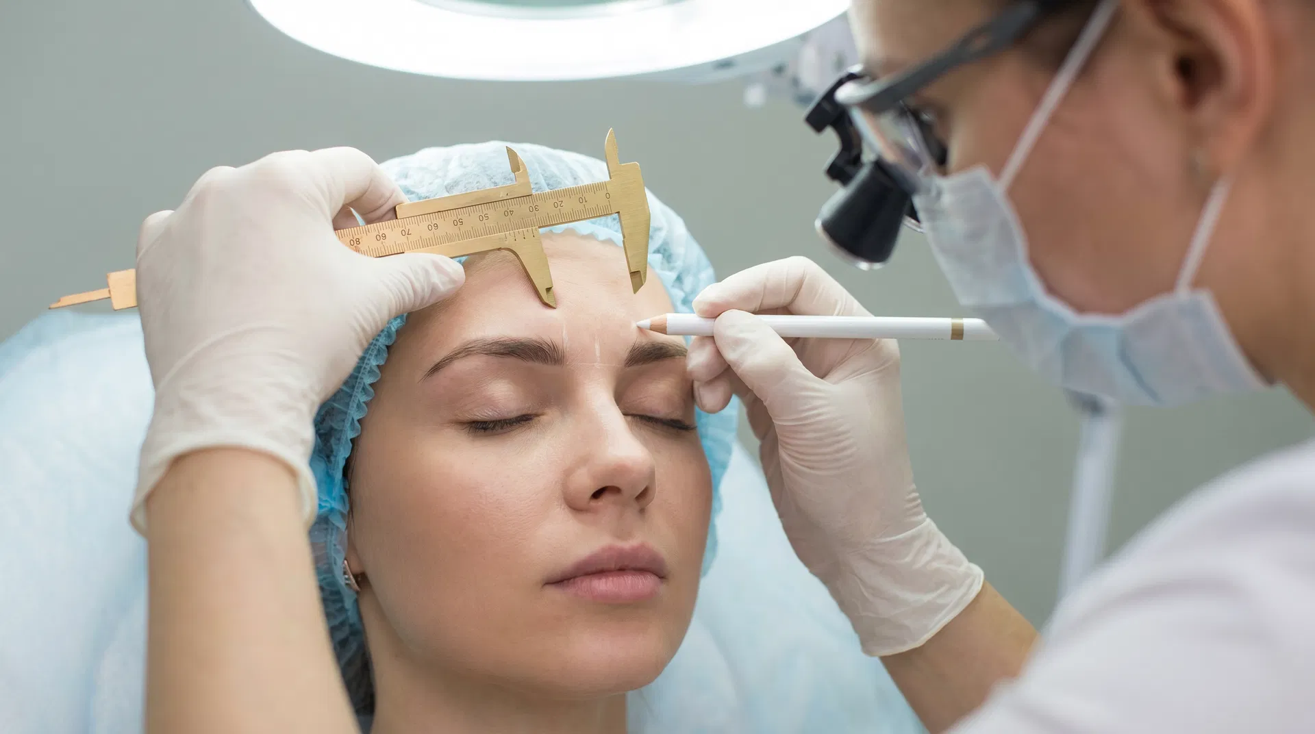 Specialist designing eyebrow shape using golden ratio measuring tool
