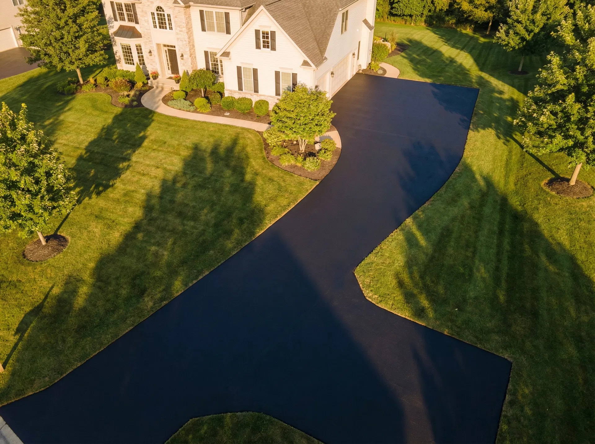 Freshly sealed black asphalt residential driveway aerial view
