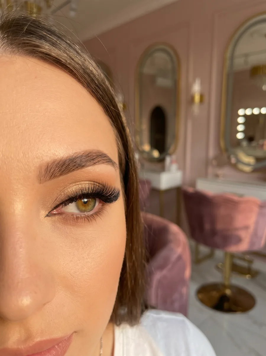 Nahaufnahme eines Auges mit vollen, dunklen Wimpernverlängerungen und goldenem Lidschatten, Ergebnis der Wimpern Grundausbild