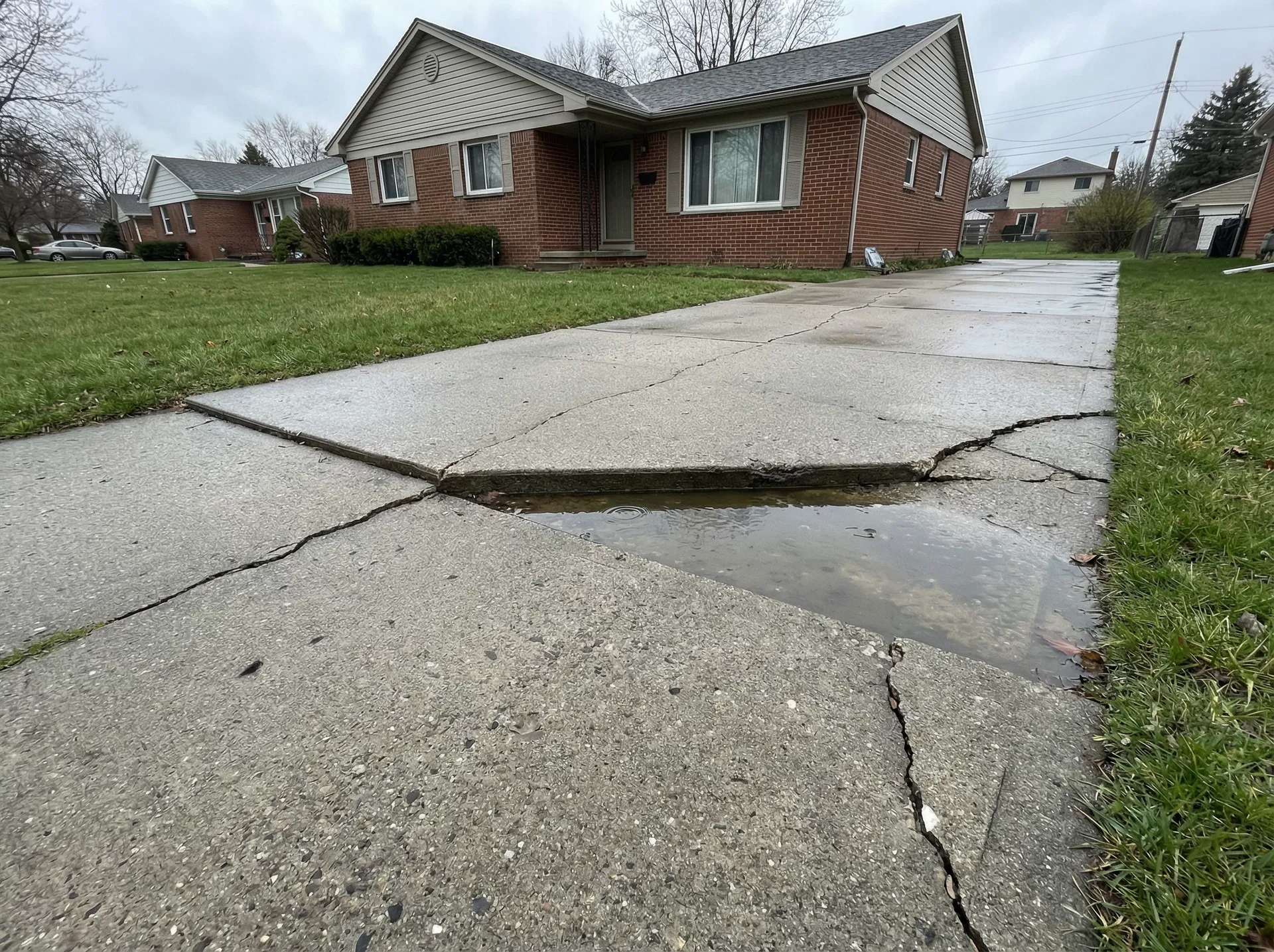 Sunken driveway slab with water pooling and cracks - needs leveling