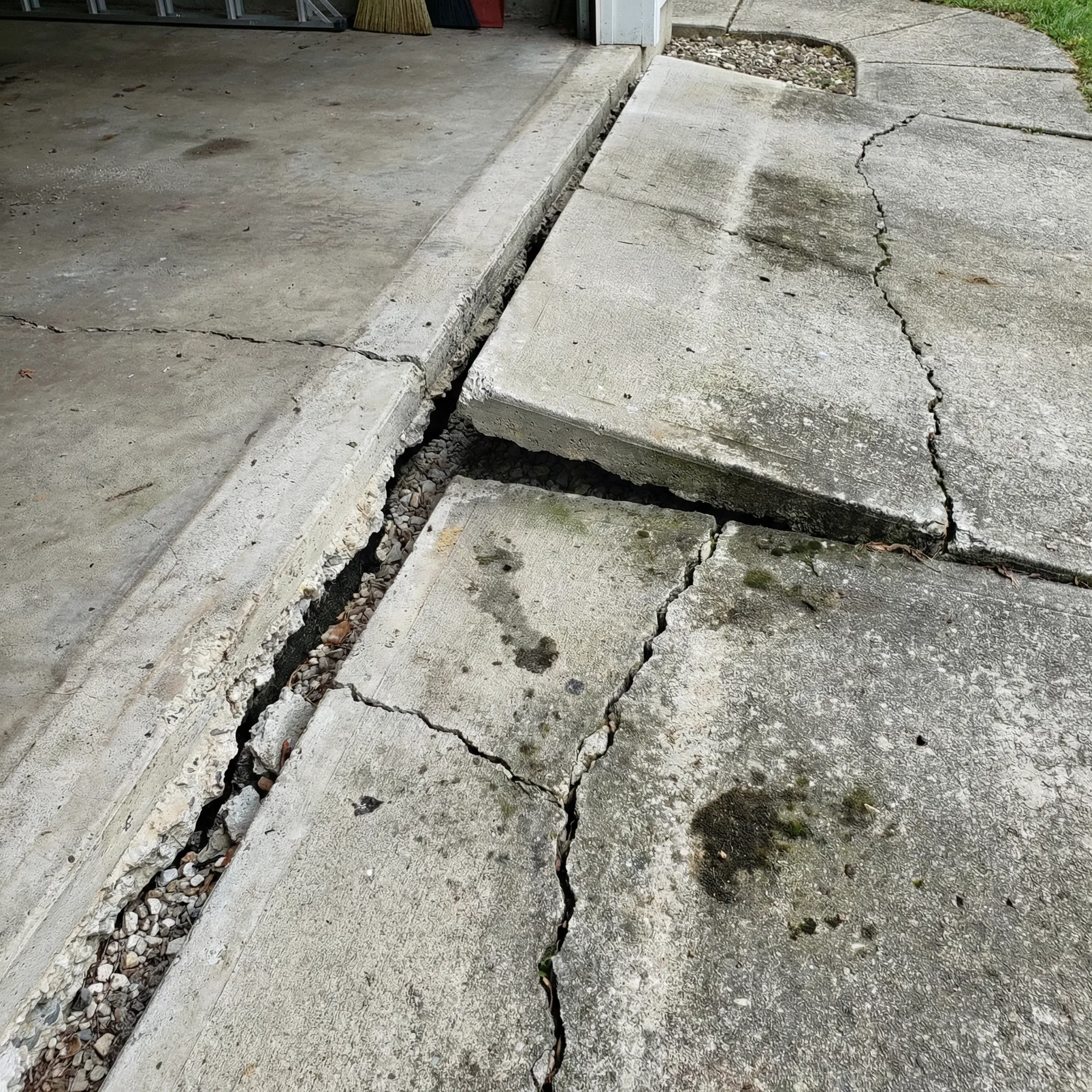 Cracked driveway at garage apron with settlement gap - needs leveling