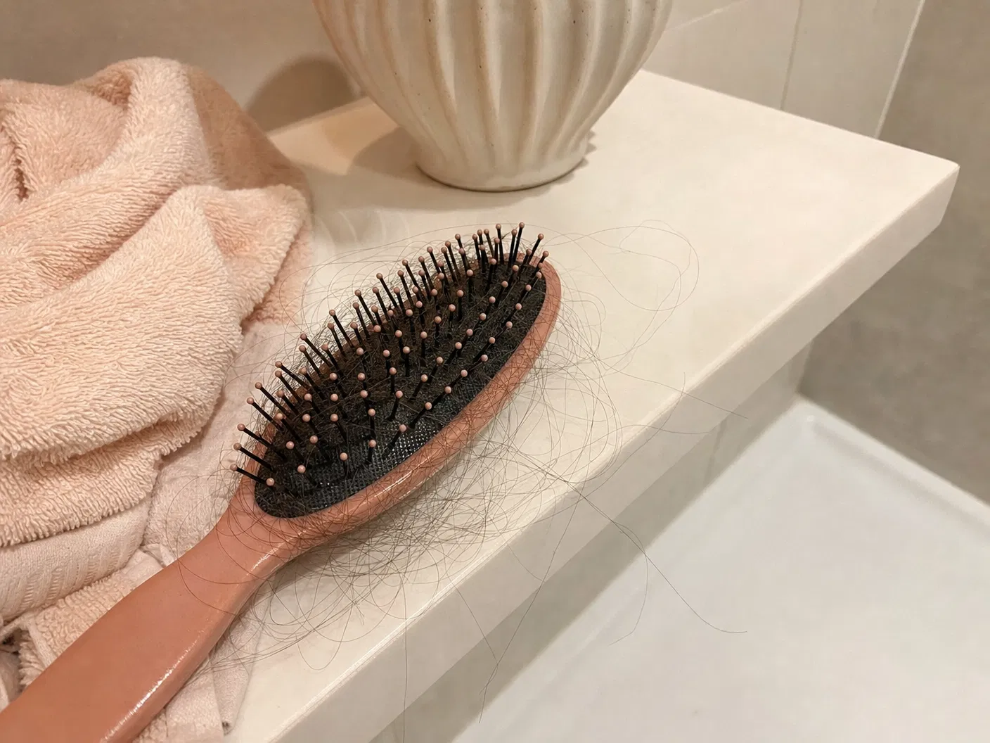 UGC style photo of hair shedding in a brush on a bathroom ledge