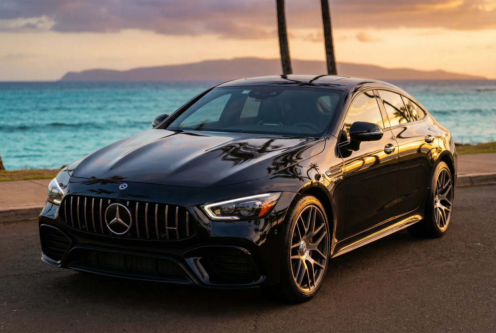 Black Mercedes-AMG sedan freshly detailed at Hawaiian oceanfront, golden hour