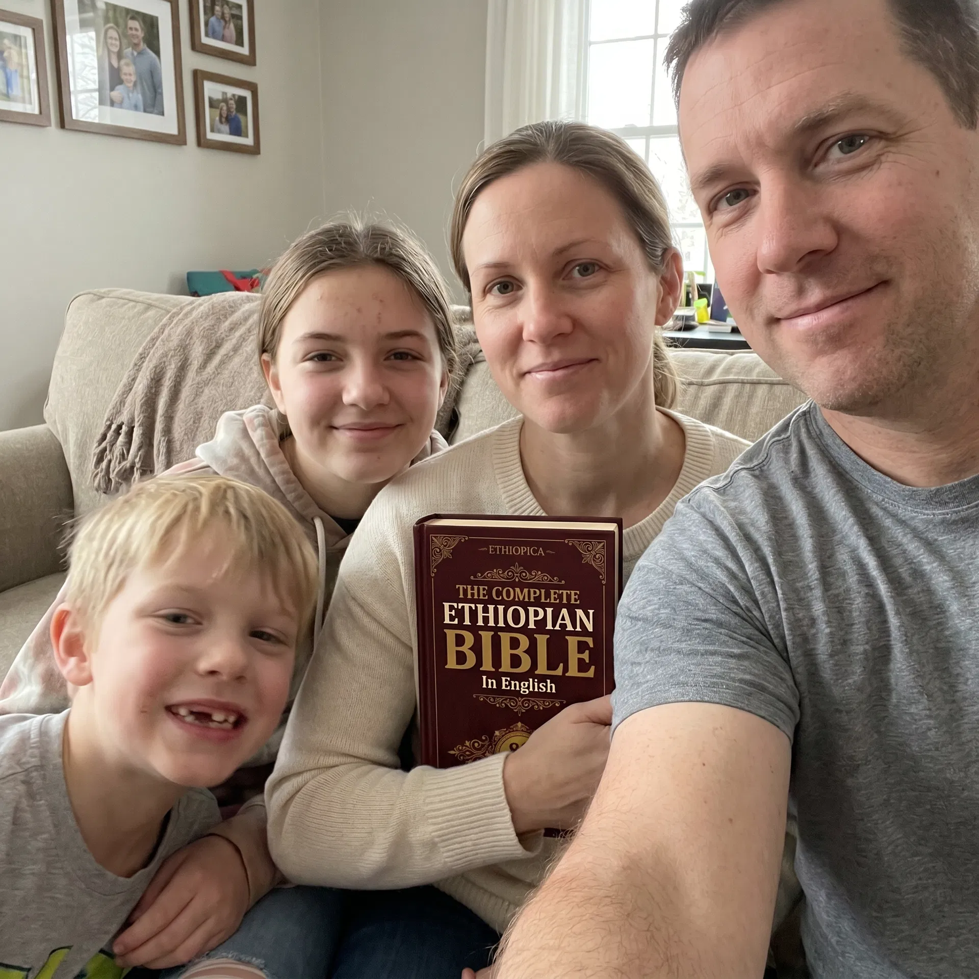 An American family of four on the couch, the mom holding The Complete Ethiopian Bible by Ethiopica