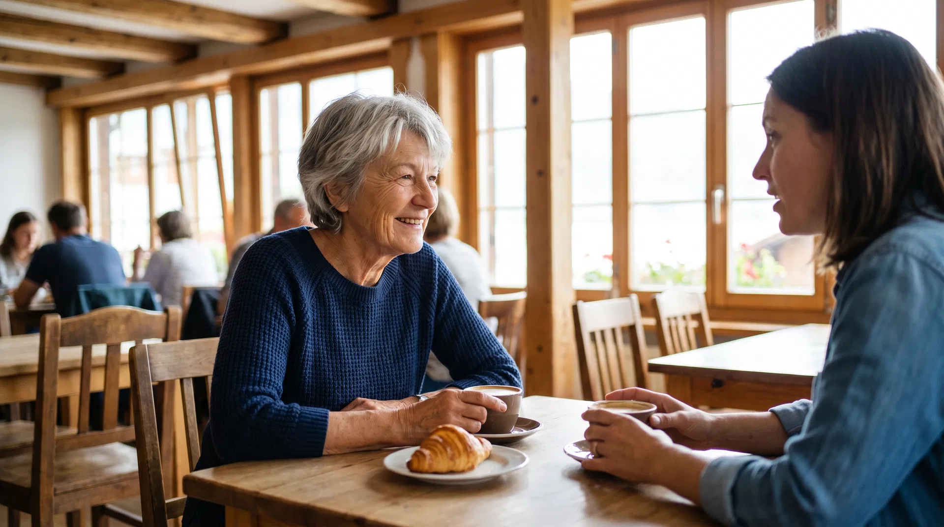 Susanne im Café mit ihrer Tochter, lehnt sich vor um besser zu hören