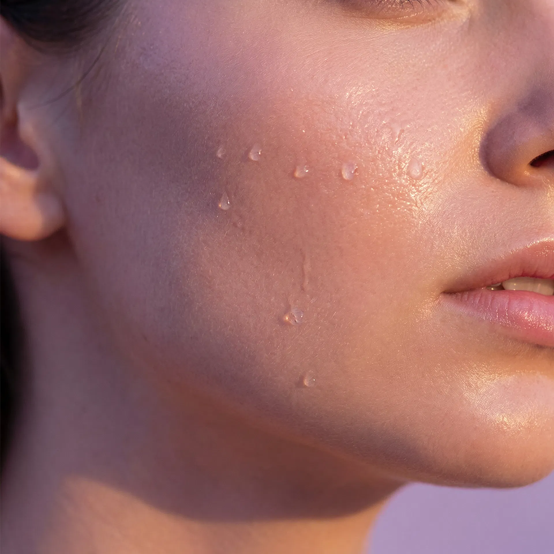 Close-up of luminous dewy glass skin with water droplets