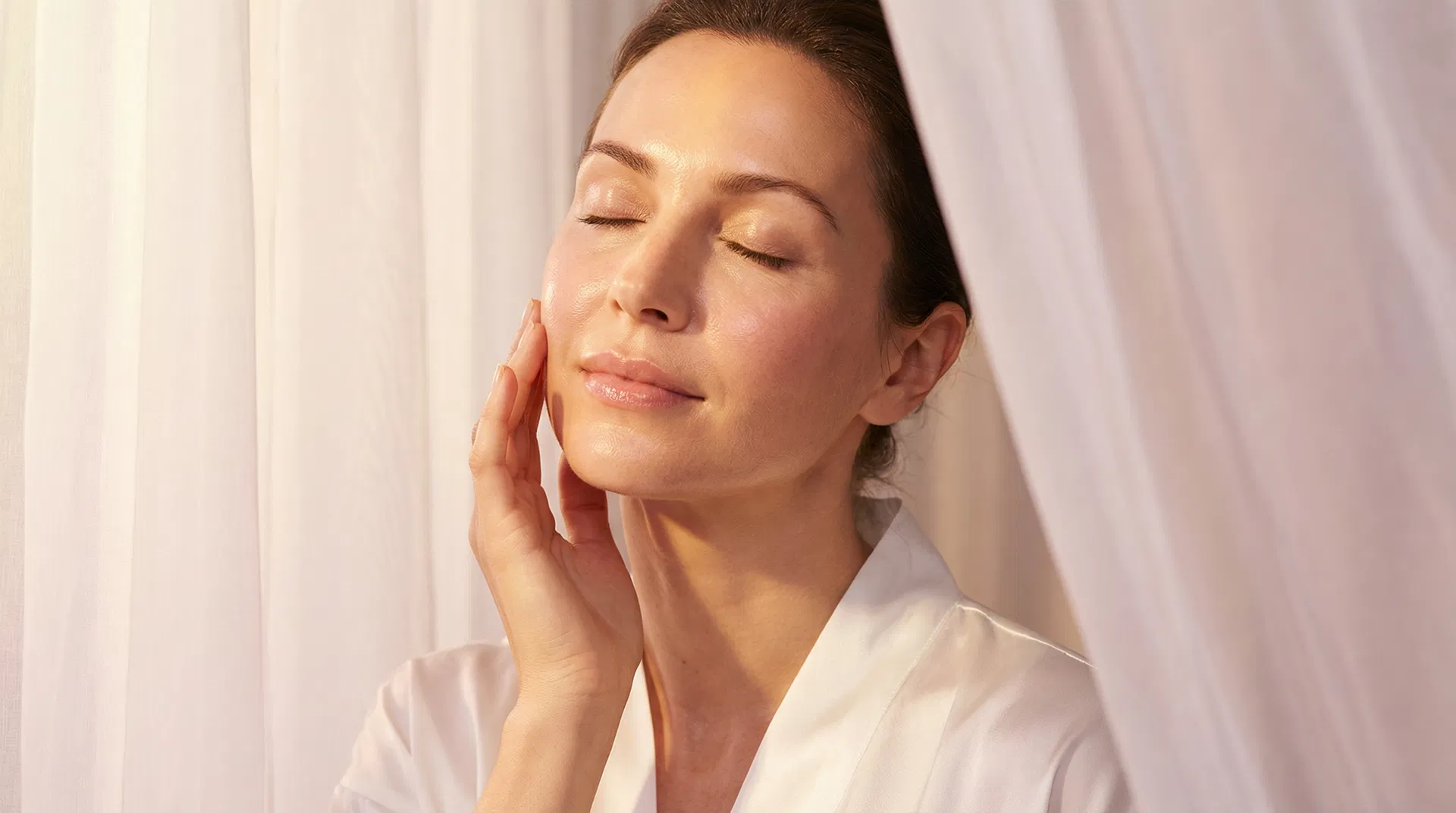 Woman with radiant glass skin touching her face