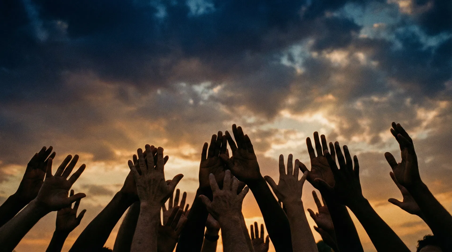 Hands raised in solidarity against the sky at golden hour