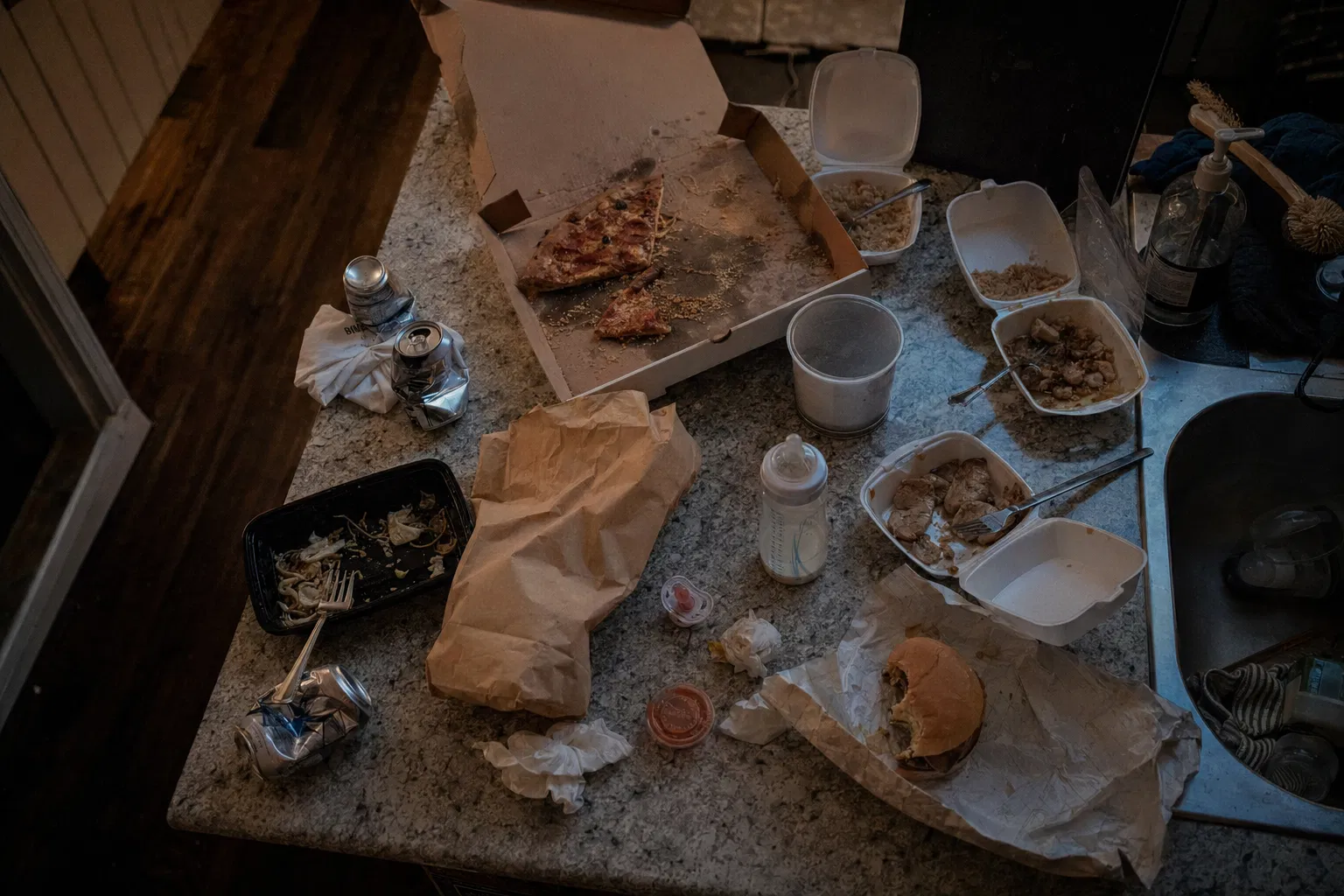 Takeout containers and baby bottle on a messy kitchen counter