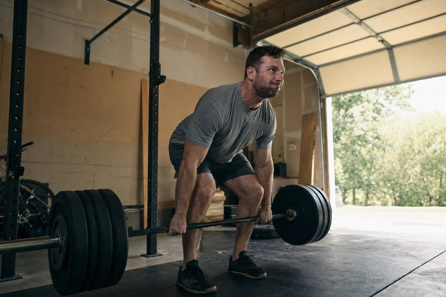 Father training with barbell in home garage gym at dawn