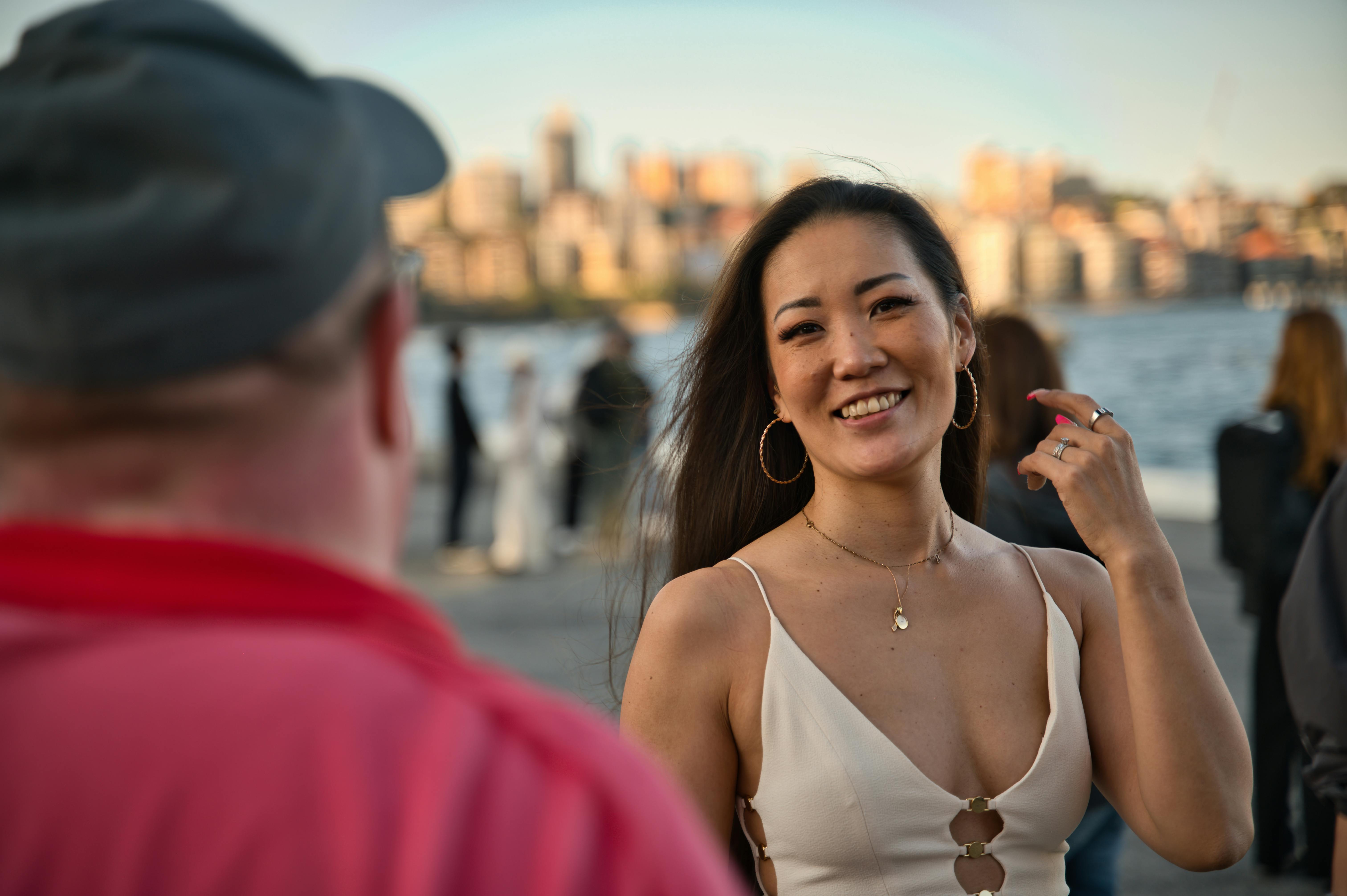 Smiling Asian Woman Interacting Outdoors by Waterfront