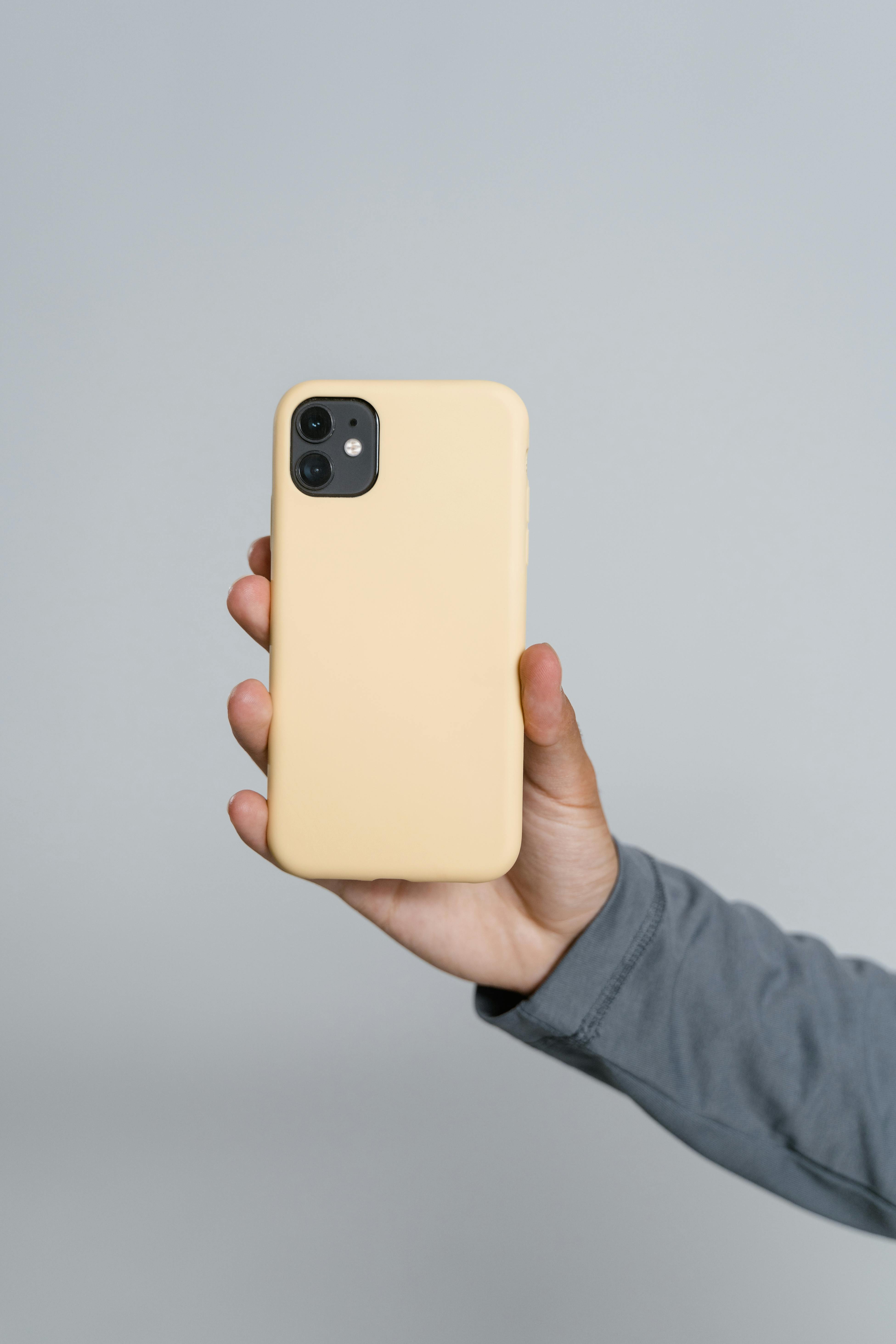Hand holding modern smartphone with yellow case