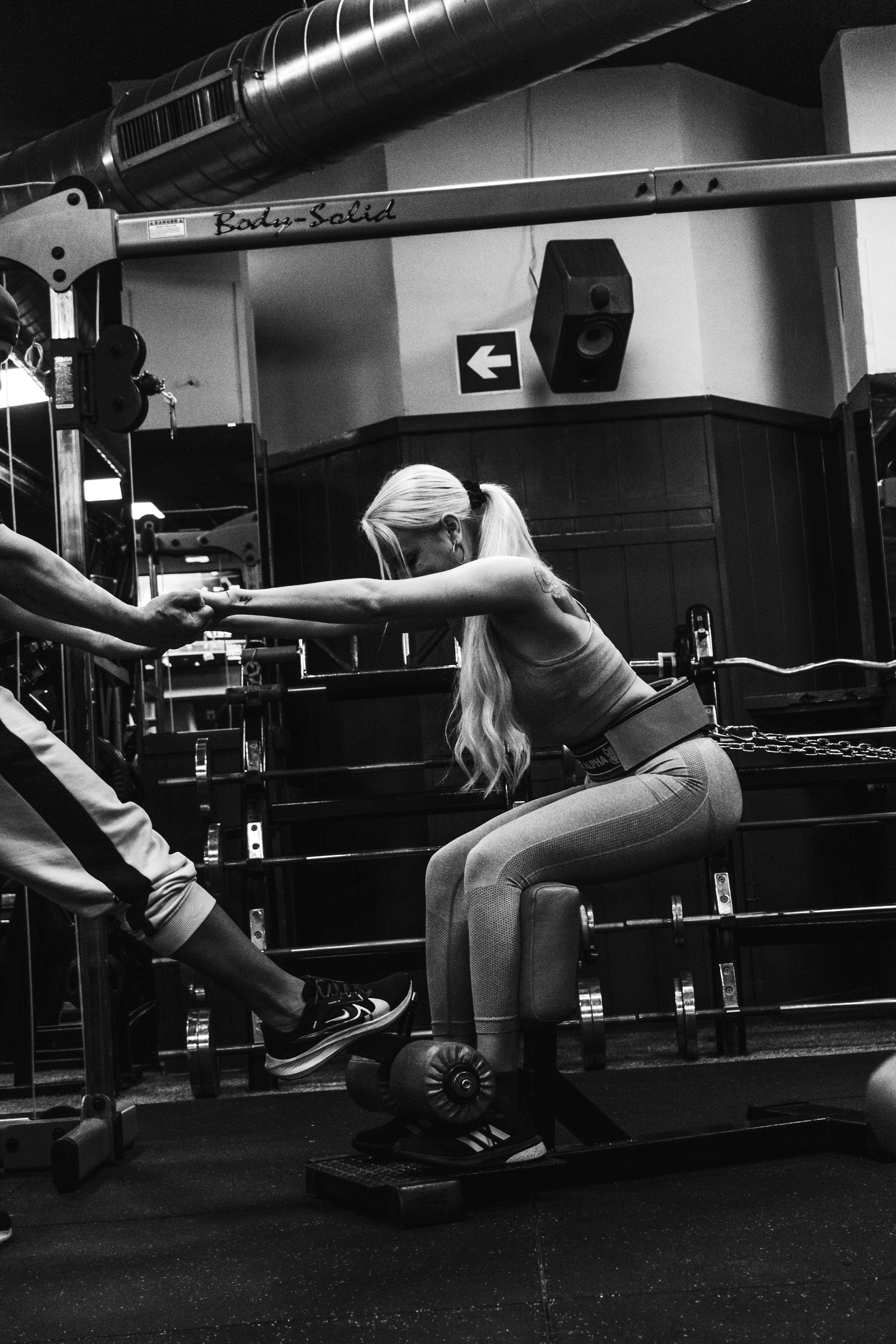 Woman training legs with assistance in gym