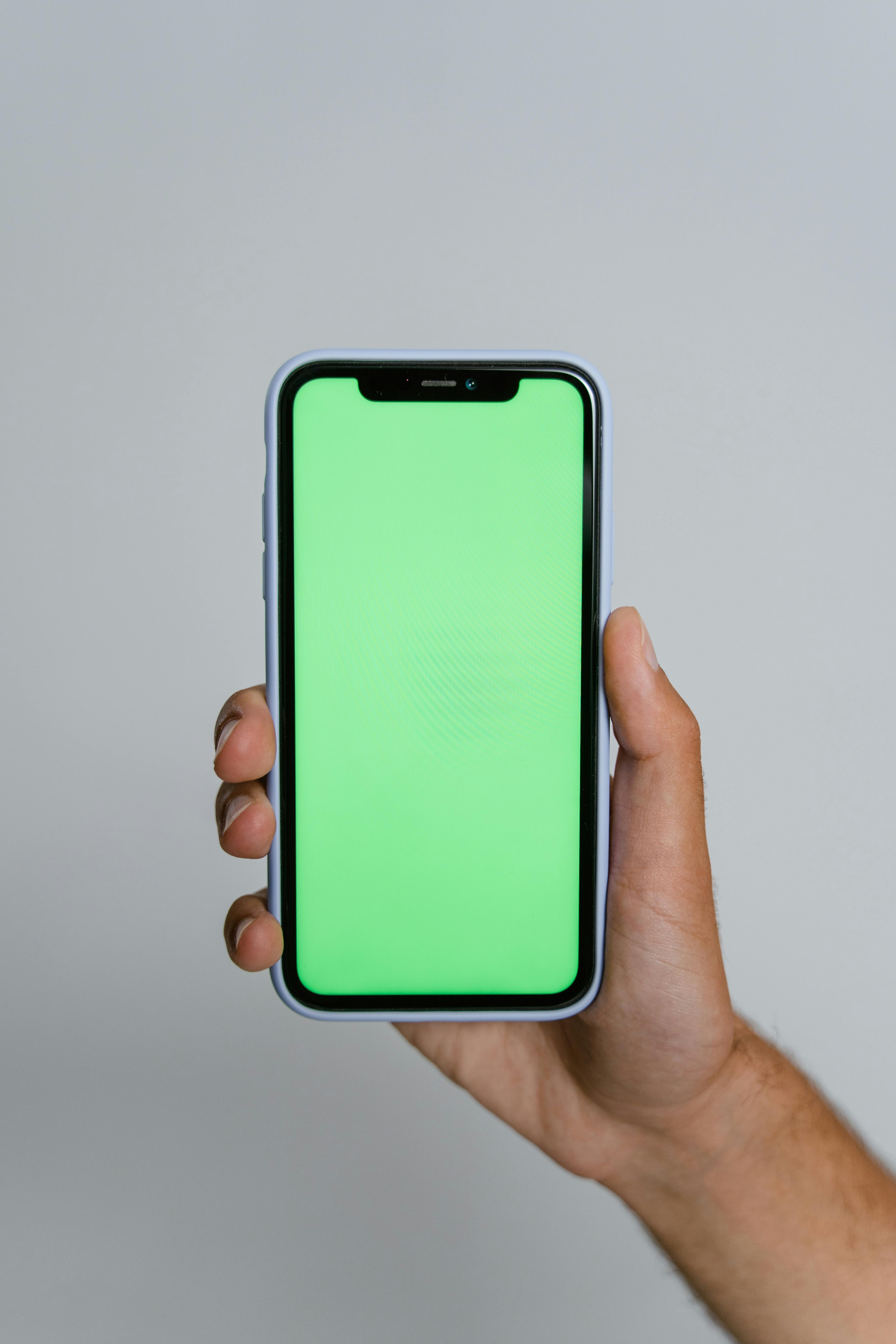Hand Holding Smartphone with Green Screen Display