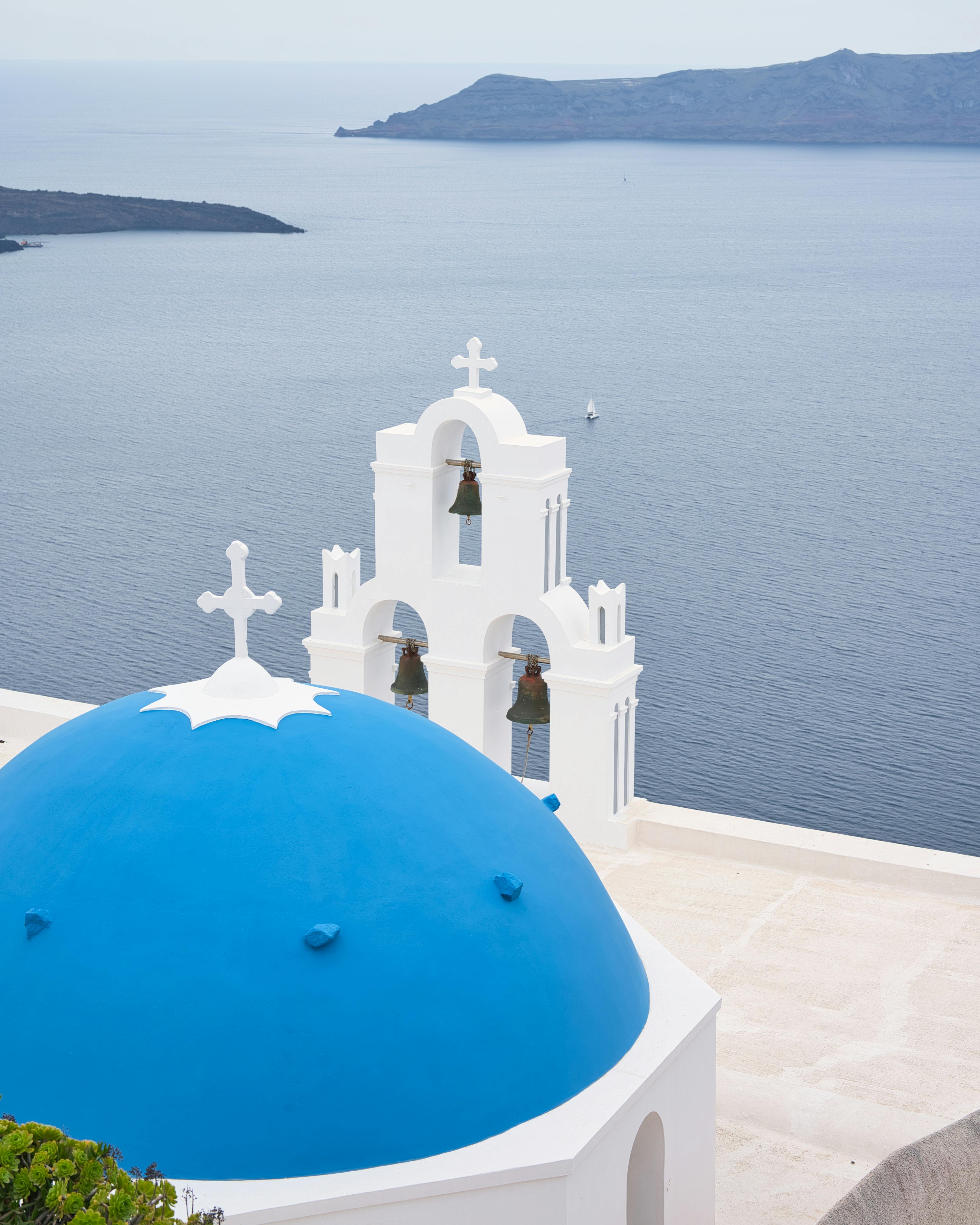 Blue-domed church and bell tower overlooking Aegean Sea