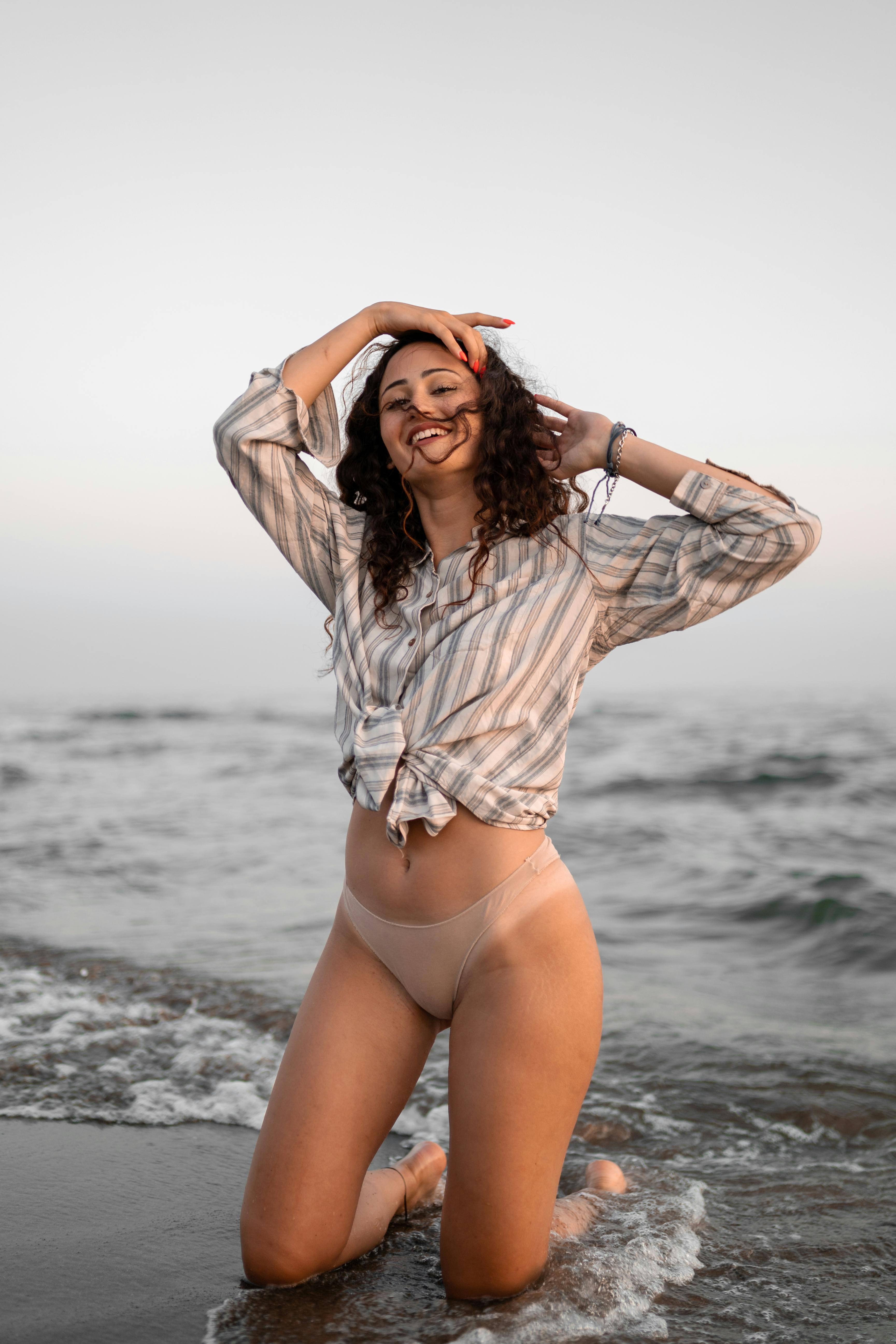 Joyful young woman kneeling in ocean waves