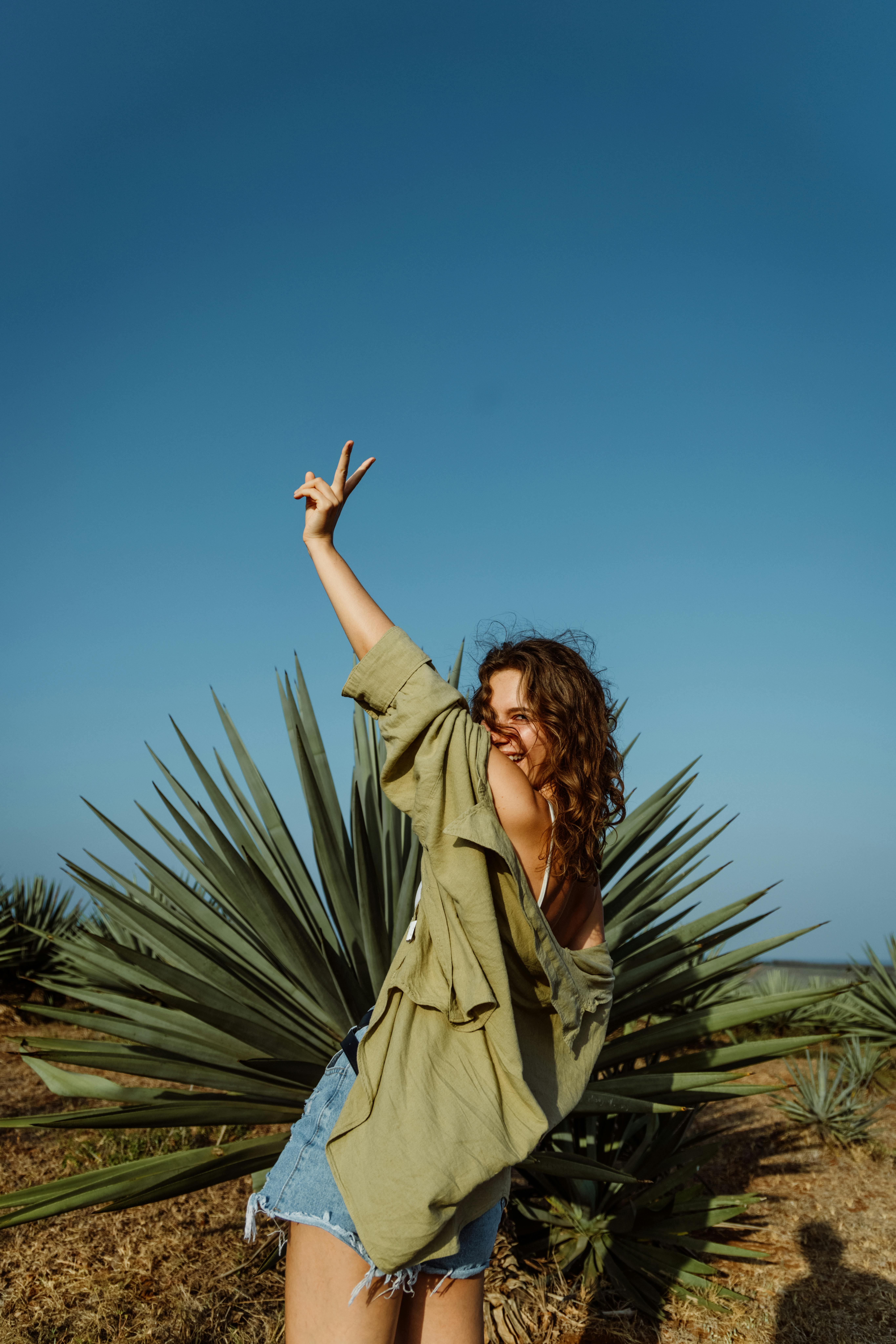 Joyful Woman Making Peace Sign in Agave Field