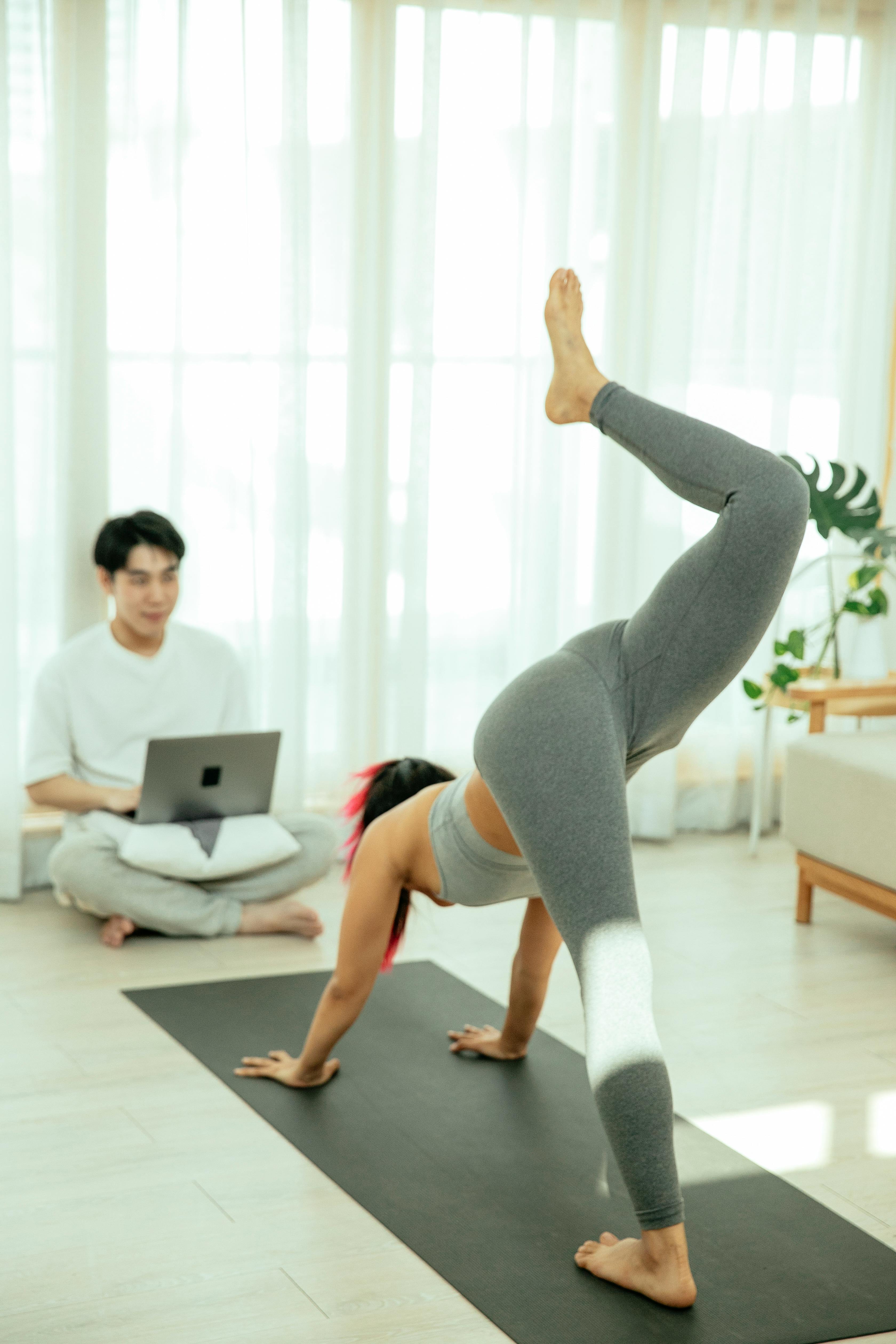 Woman doing yoga at home, man working