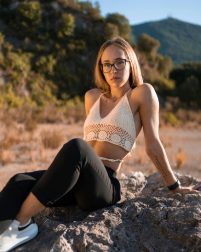 Young Woman in Glasses Sitting on Rock at Golden Hour