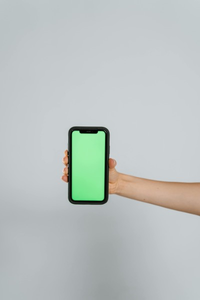 Hand Holding Smartphone with Green Screen Display