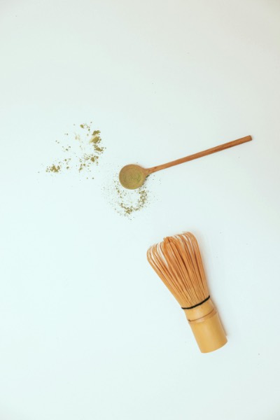 Matcha powder and whisk on white background