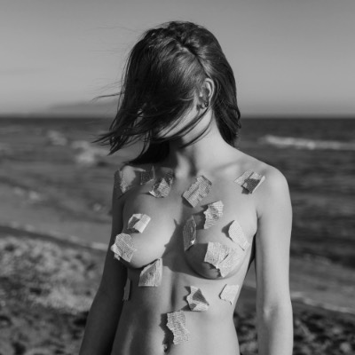 Woman with cardboard pieces on chest by sea